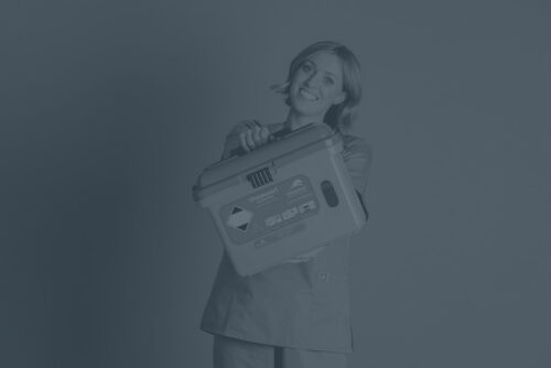Female nurse smiling and holding a Sharpsmart container