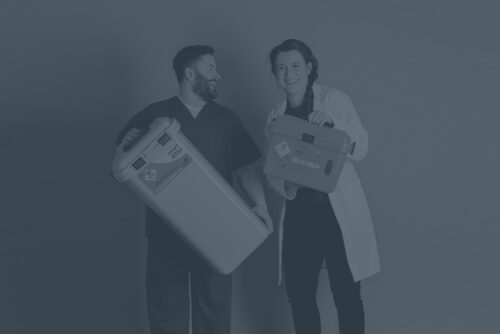 Male nurse and female nurse holding and smiling with two different Sharpsmart containers