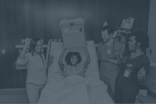 Young female holding a Sharpsmart container with nurses and her mother celebrating around her